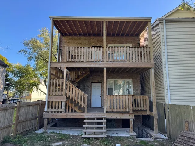 a view of wooden house with large windows and a small yard