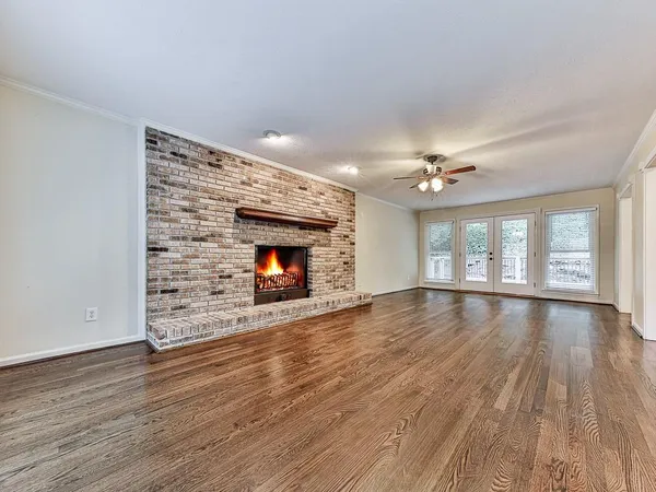 a view of an empty room with wooden floor fireplace and a window