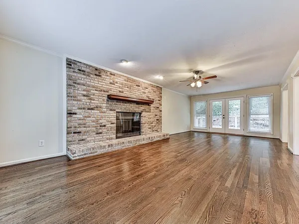 a view of an empty room with wooden floor and a fireplace