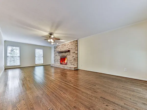 a view of a livingroom with wooden floor a ceiling fan and windows