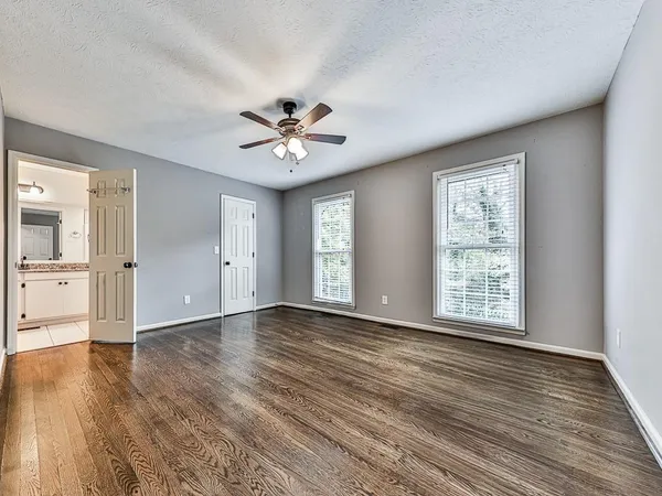 a view of an empty room with a window and wooden floor