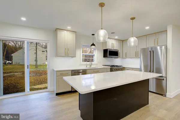 a kitchen with kitchen island a counter space a sink appliances and cabinets