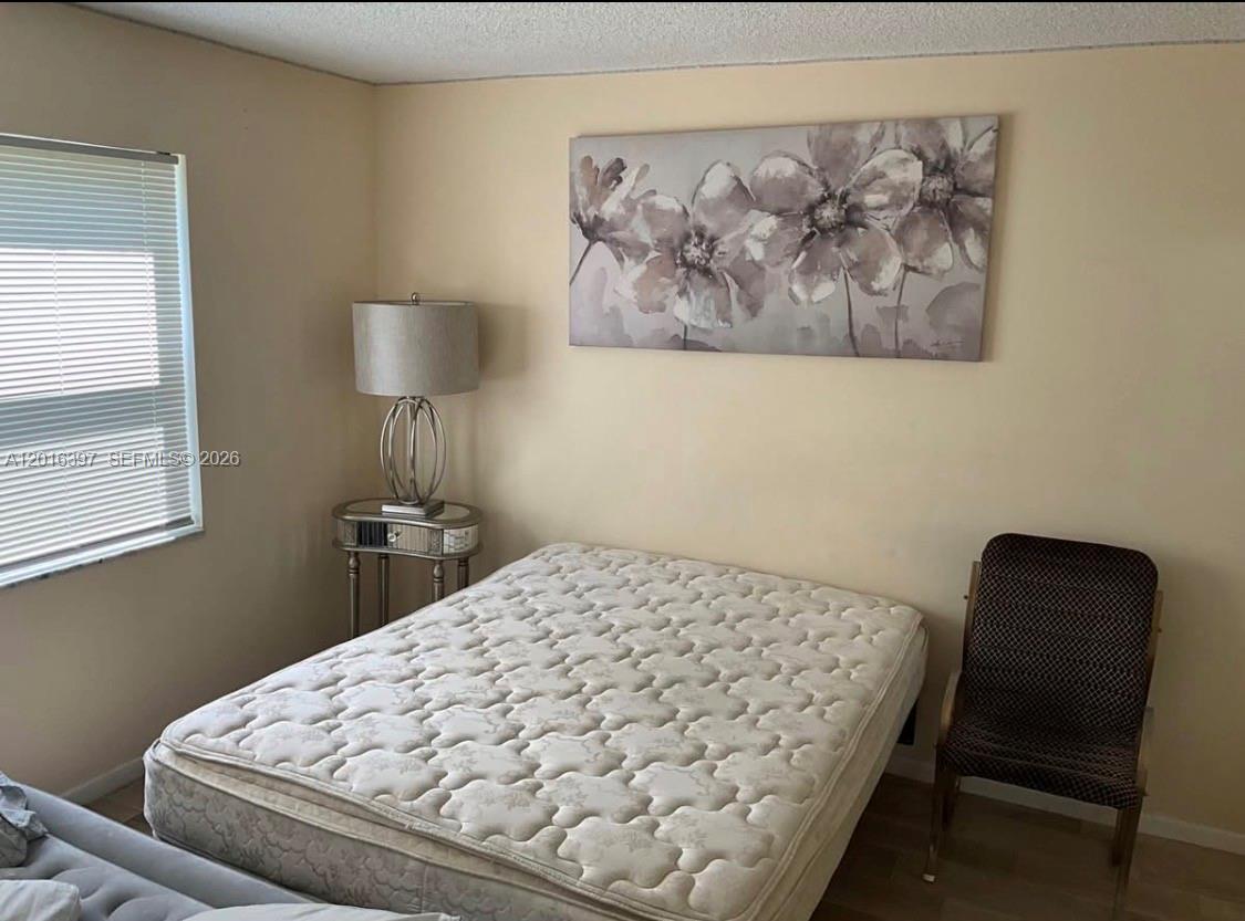 151 Berkley Road, Unit 303 Hollywood, FL 33024 - Photo 8 of 11 a bedroom with a bed and a chair