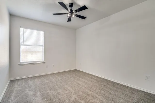 an empty room with a window and a fan