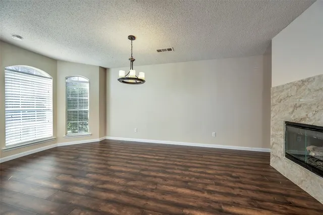 an empty room with wooden floor fireplace and windows