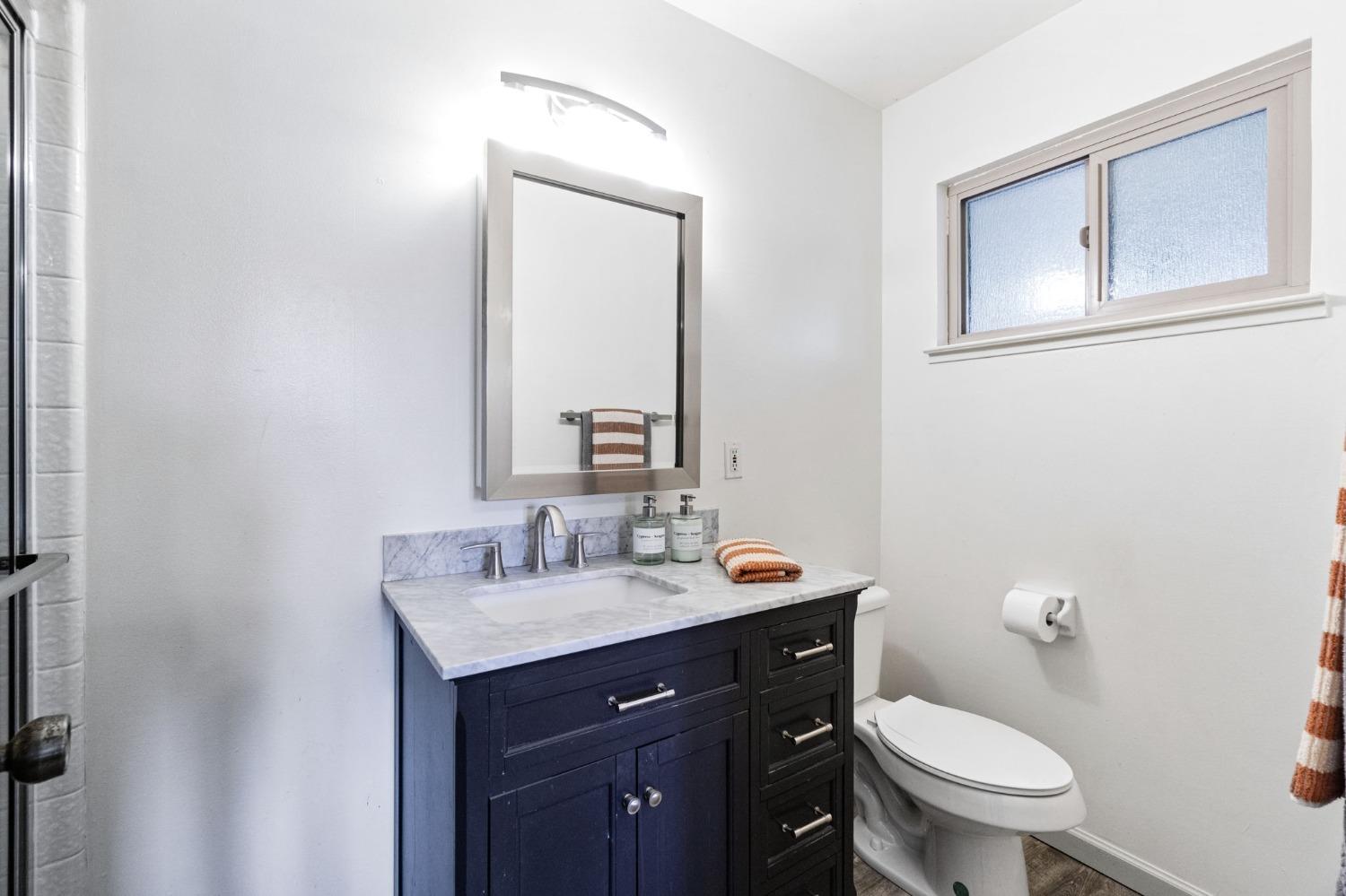 918 East Griffith Way Fresno, CA 93704 - Photo 9 of 21 a bathroom with a toilet a sink a vanity and mirror