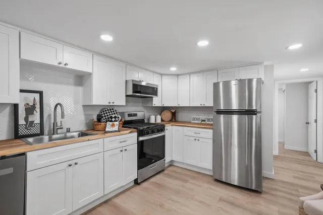a kitchen with white cabinets stainless steel appliances and wooden floors