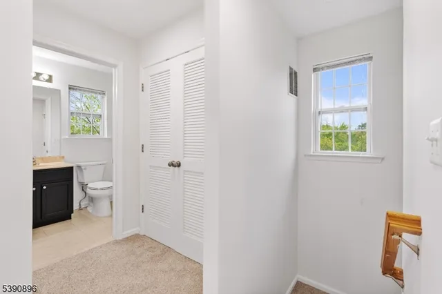 a view of a hallway with bathroom and a sink