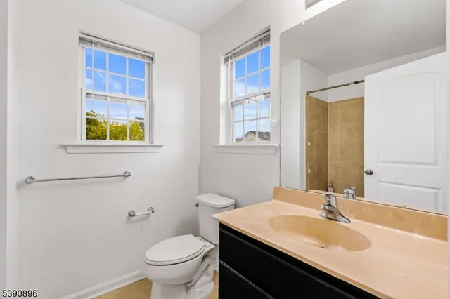 a bathroom with a granite countertop sink a toilet and a window