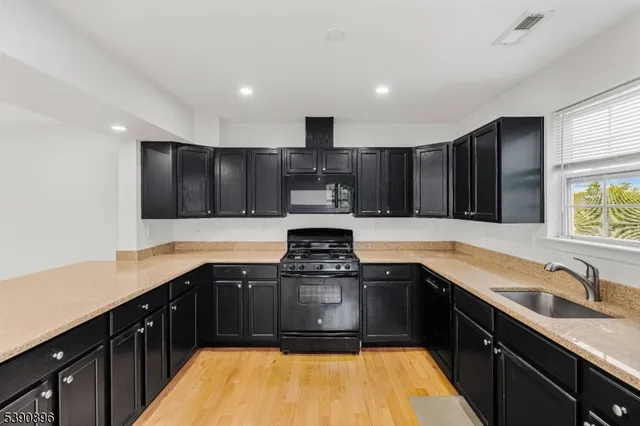 a kitchen with kitchen island granite countertop stainless steel appliances a sink stove top oven and cabinets