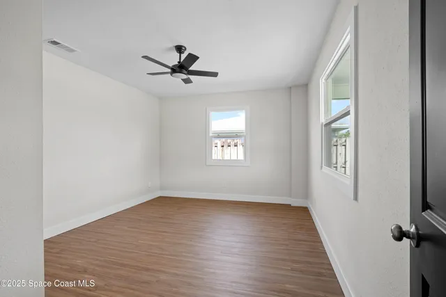 a view of empty room with wooden floor and fan