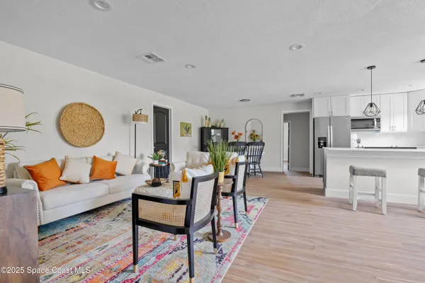 a living room with furniture kitchen view and a wooden floor