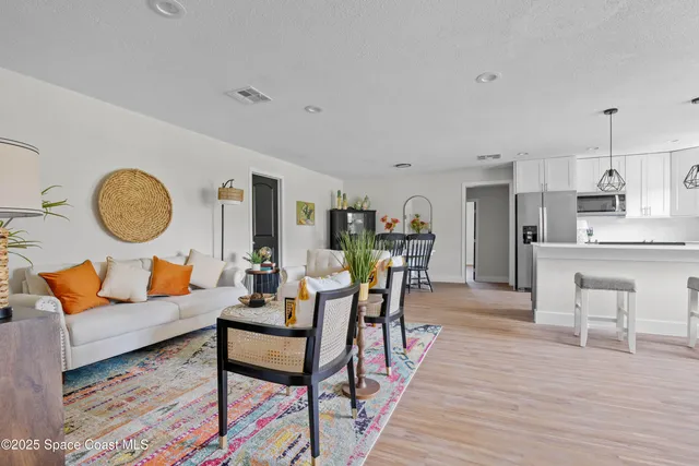 a living room with furniture kitchen view and a wooden floor