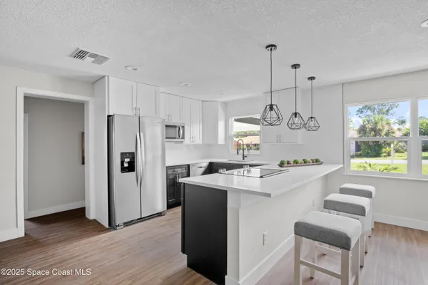 a kitchen with kitchen island white cabinets and refrigerator