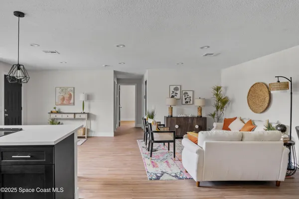 a living room with furniture kitchen view and a wooden floor