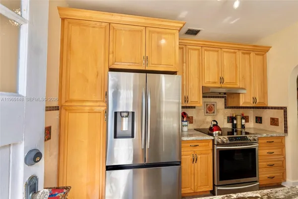 a kitchen with stainless steel appliances granite countertop a refrigerator a stove and a sink with large window