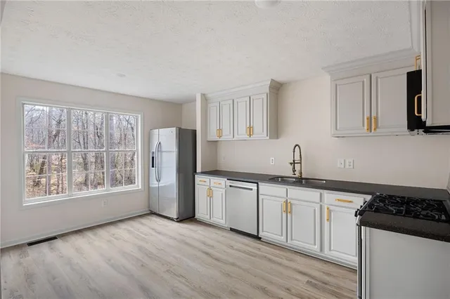 a kitchen with stainless steel appliances granite countertop a stove a sink and a refrigerator