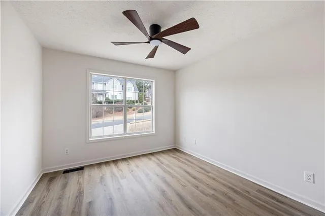 an empty room with wooden floor ceiling fan and windows