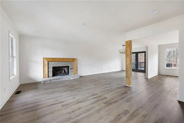 an empty room with wooden floor fireplace and windows
