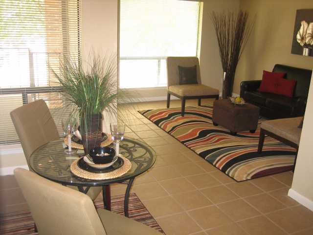 a view of a dining room with furniture a potted plant and a window