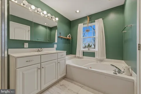 a bathroom with a tub a sink and mirror