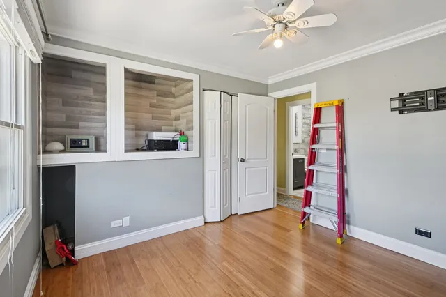 a view of empty room with wooden floor and fan