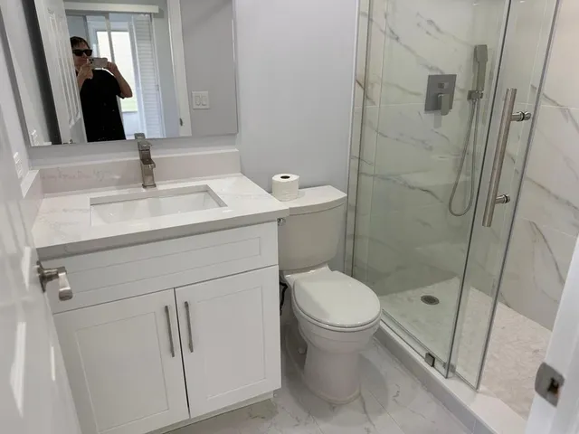 a bathroom with a sink a toilet and shower