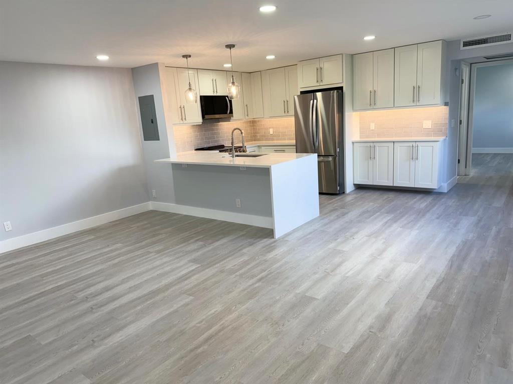 214 Monaco Boulevard, Unit 214 Delray Beach, FL 33446 - Photo 6 of 22 a kitchen with kitchen island wooden cabinets a refrigerator and a sink