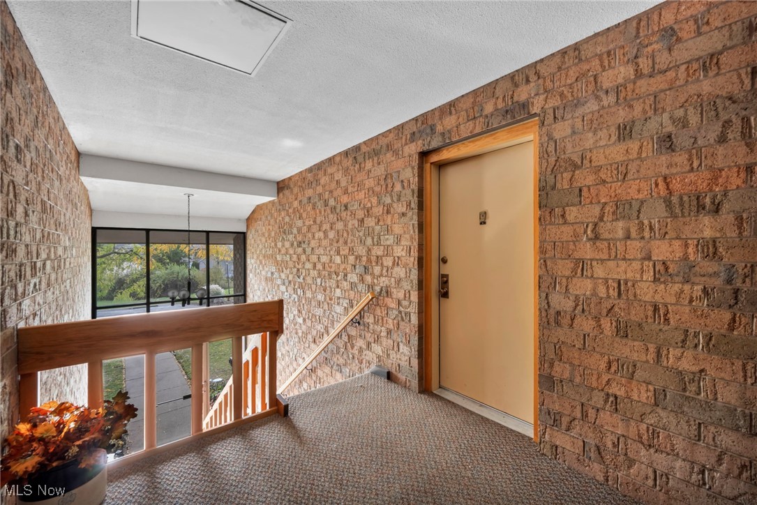 1263 Lost Nation Road, Unit 5 Willoughby, OH 44094 - Photo 4 of 26 Hall with an upstairs landing, a textured ceiling, carpet floors, brick wall, and elevator