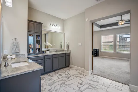 a bathroom with a sink vanity granite tub and a mirror