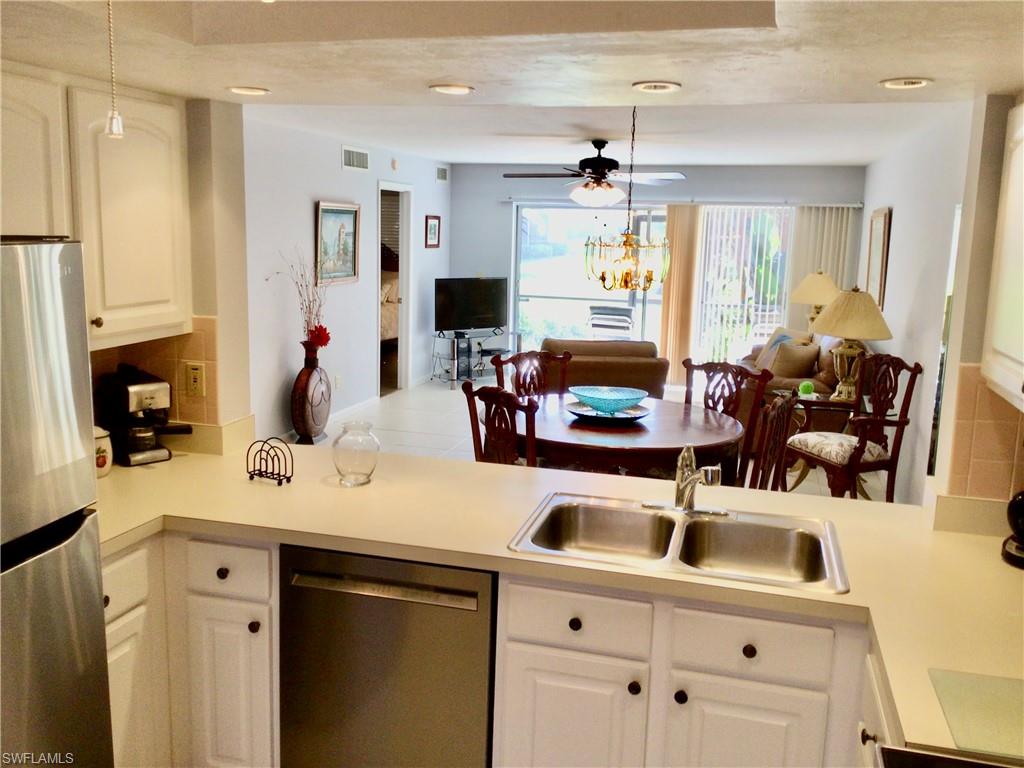a kitchen with stainless steel appliances kitchen island granite countertop a sink and dishwasher with white cabinets