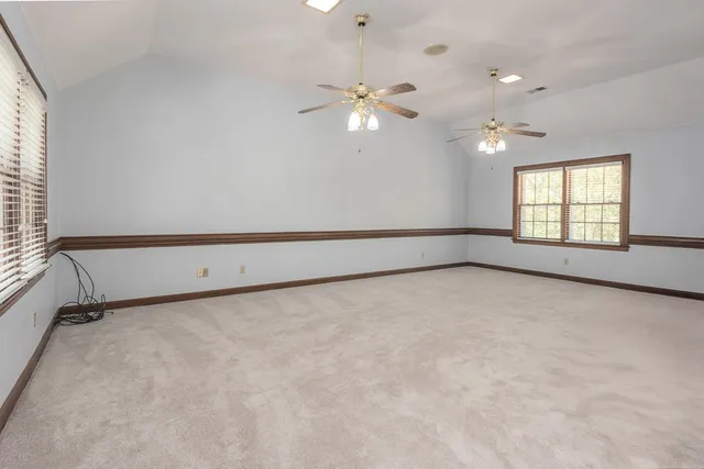 an empty room with windows and ceiling fan