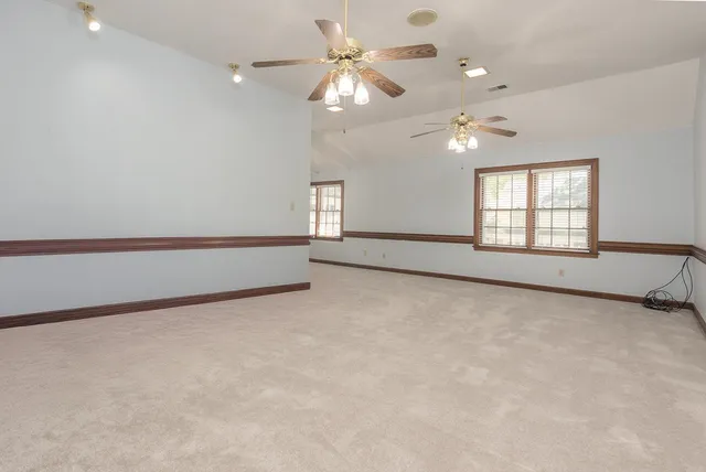 an empty room with windows and fan