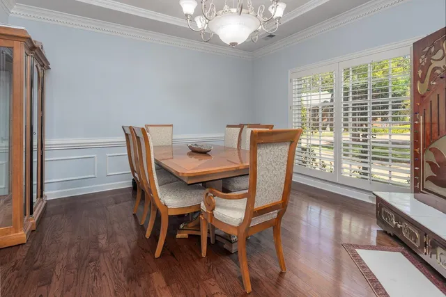 a dining room with furniture wooden floor a potted plant and a chandelier