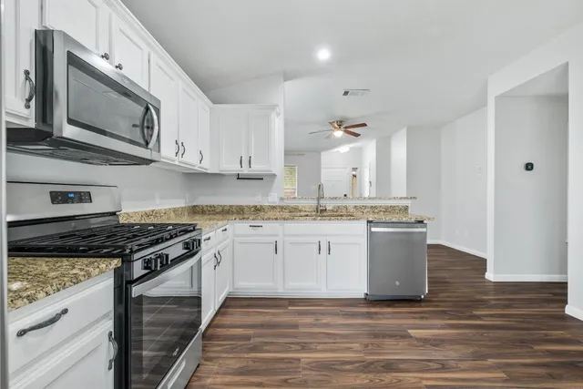 a kitchen with stainless steel appliances granite countertop a stove a sink and a microwave