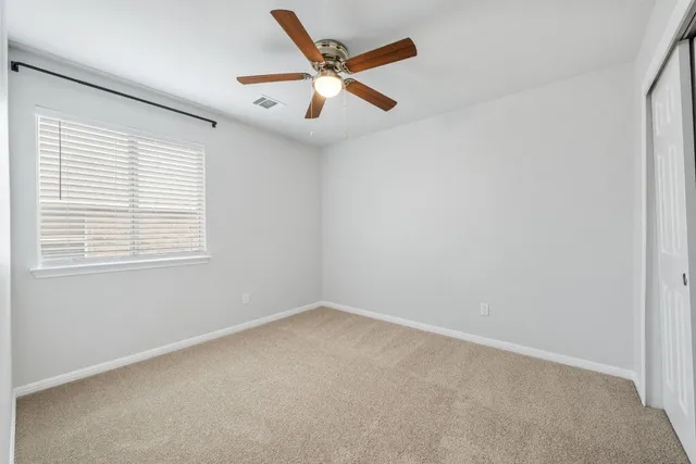 an empty room with ceiling fan and windows