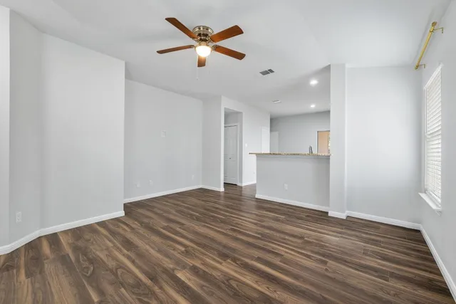 a view of an empty room with wooden floor and a window
