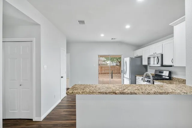 a living room with stainless steel appliances granite countertop furniture and a wooden floor