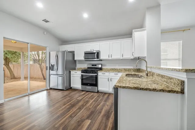 a kitchen with granite countertop a sink stove and refrigerator