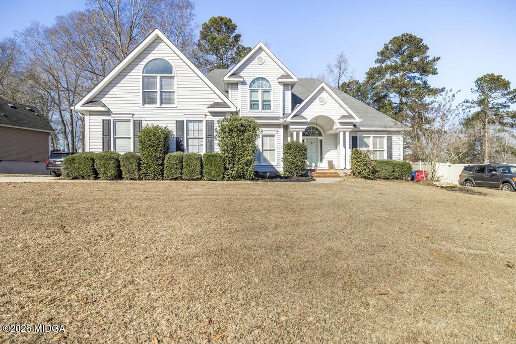 128 Springwood Court Macon, GA 31210 - Photo 1 of 21 a view of a white house with a yard and large trees