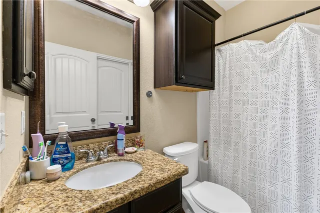 a bathroom with a granite countertop toilet sink and mirror