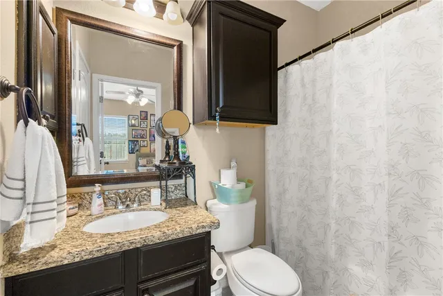 a bathroom with a granite countertop sink and a mirror with toilet