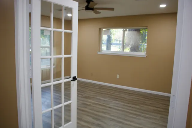an empty room with wooden floor and windows
