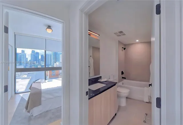 a bathroom with a granite countertop sink a toilet a mirror and shower