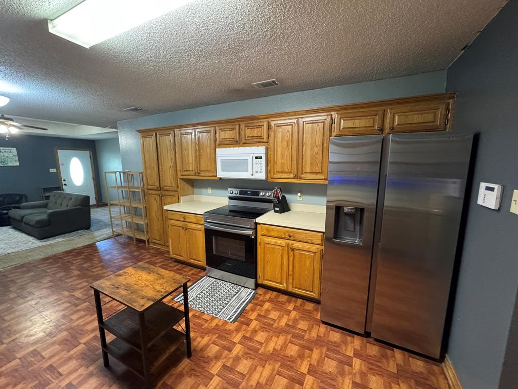 705 East James Street Wills Point, TX 75169 - Photo 11 of 26 a kitchen with stainless steel appliances granite countertop a refrigerator a stove a sink a dining table and chairs with wooden floor
