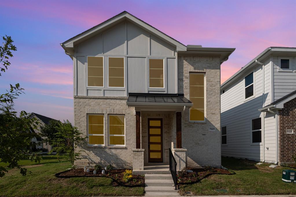 Modern home with a standing seam roof, a front lawn, brick siding, and a metal roof