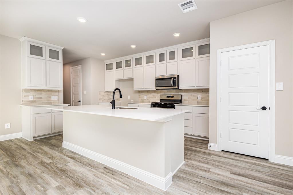 7221 Bayhill Drive Rowlett, TX 75088 - Photo 6 of 18 Kitchen with white cabinetry, stainless steel appliances, glass insert cabinets, recessed lighting, and a kitchen island with sink