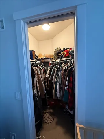 a view of walk in closet with clothes and shoes