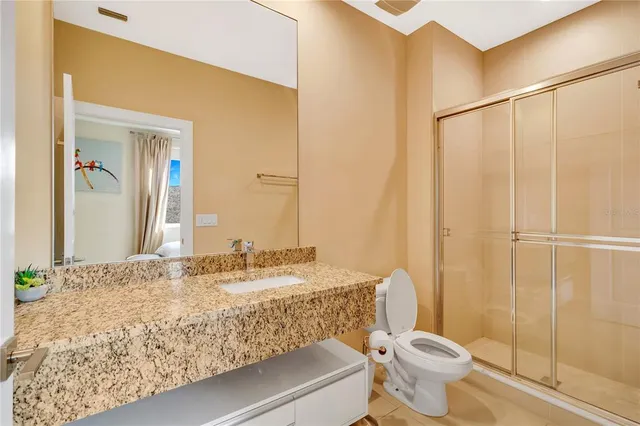 a bathroom with a granite countertop sink mirror vanity and toilet