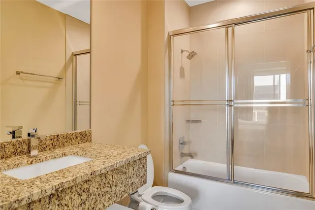 a bathroom with a granite countertop shower sink and toilet